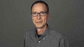 Porträt von Frank Bergmann vor neutralem Hintergrund.