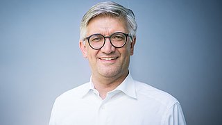 Porträt von Martin Handschuh vor einem neutralen Hintergrund.