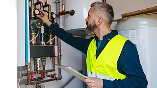 Handwerker stellt Heizungsanlage im Heizungskeller ein – digitales Heizungsmonitoring für mehr Effizienz.