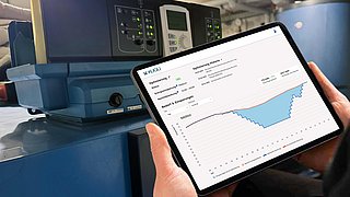 Auf dem Bild in zu ein Tablet mit dem Kundenportal zu sehen, auf dem Einsparung in einer Kurve aufgezeigt wird.
