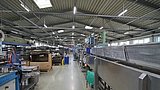 Eine Werkshalle des Unternehmens. An der Decke hängt die moderne Beleuchtungsanlage.