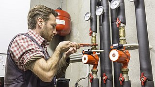Installateur bei der Montage einer Umwälzpumpe für ein Heizungs- oder Wassersystem.