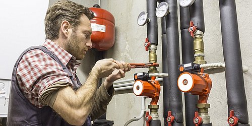 Installateur bei der Montage einer Umwälzpumpe für ein Heizungs- oder Wassersystem.