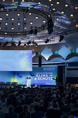 Der große Veranstaltungssaal des Kongresses. Hunderte Menschen sitzen auf Stühlen und schauen auf die Bühne zum Redner Robert Habeck.
