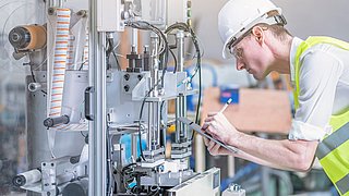 Maschinenbauingenieur prüft eine montierte Maschine in einer Fabrikhalle.