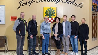 Eine Gruppe von sieben Personen steht im Foyer der Schule