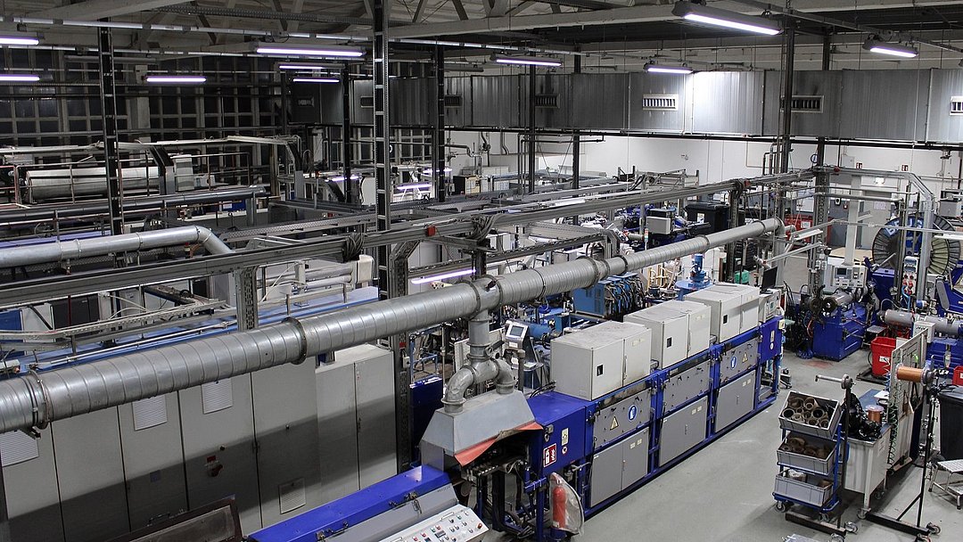 Eine Werkshalle des Unternehmens. An der Decke hängt die moderne Beleuchtungsanlage.