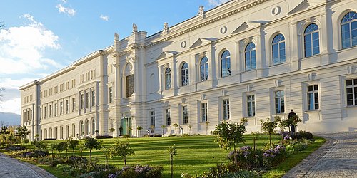 Außenansicht des Hauptgebäudes der Leopoldina in Halle. Davor ist ein begrünter Garten.