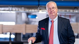 Thomas Kübler steht in einer Produktionshalle.